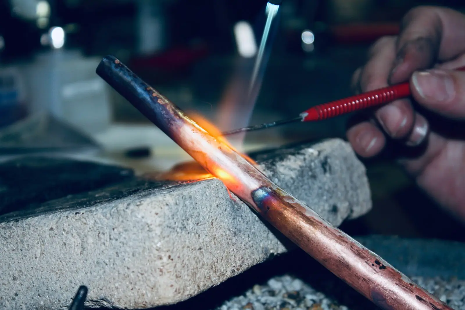 Copper pipe glowing under a torch flame during soldering