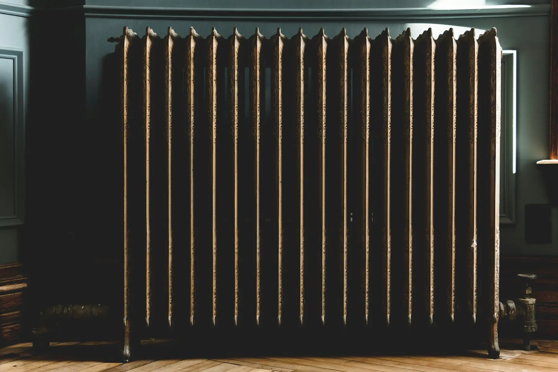 Cast-iron radiator warming a dark-panelled New England room