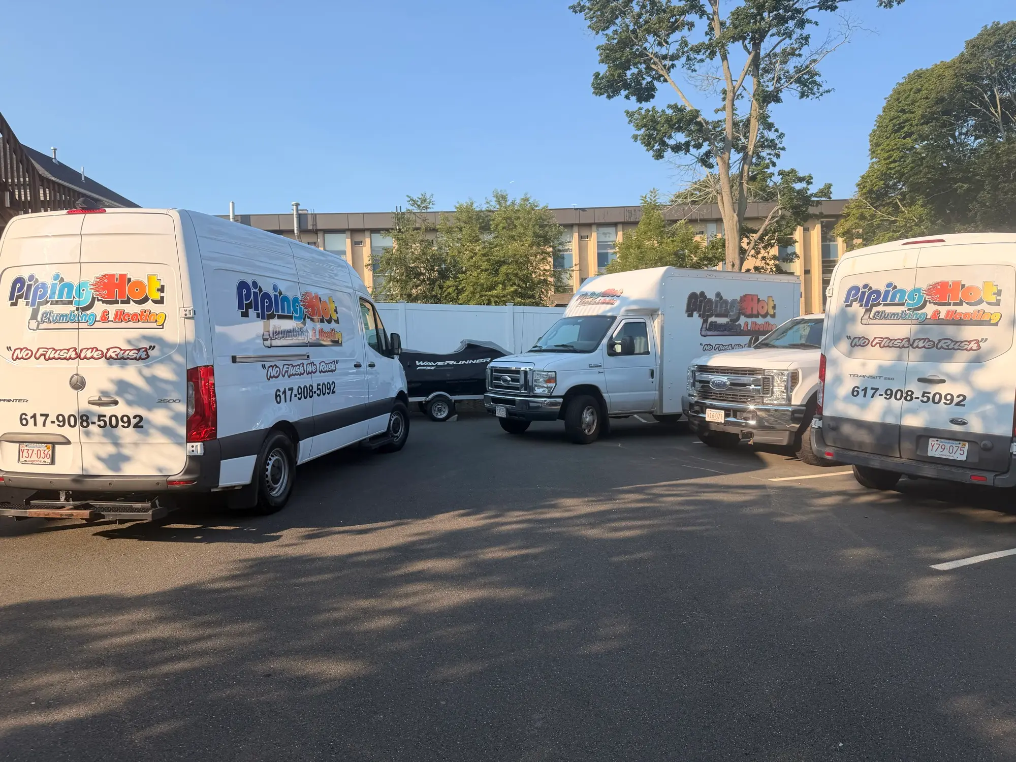Piping Hot Plumbing & Heating service vans lined up, showing the company logo and phone number